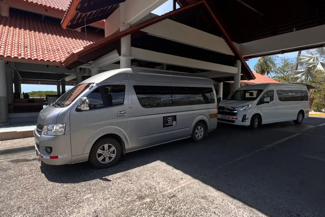 Guana Shuttle Service vans waiting under a hotel entrance canopy in Guanacaste
