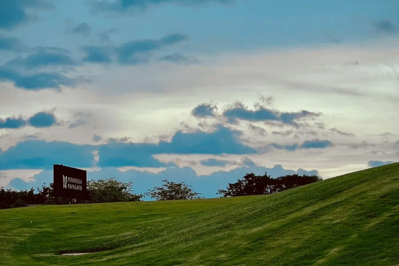 The Peninsula Papagayo entrance sign on the green hillside at dusk