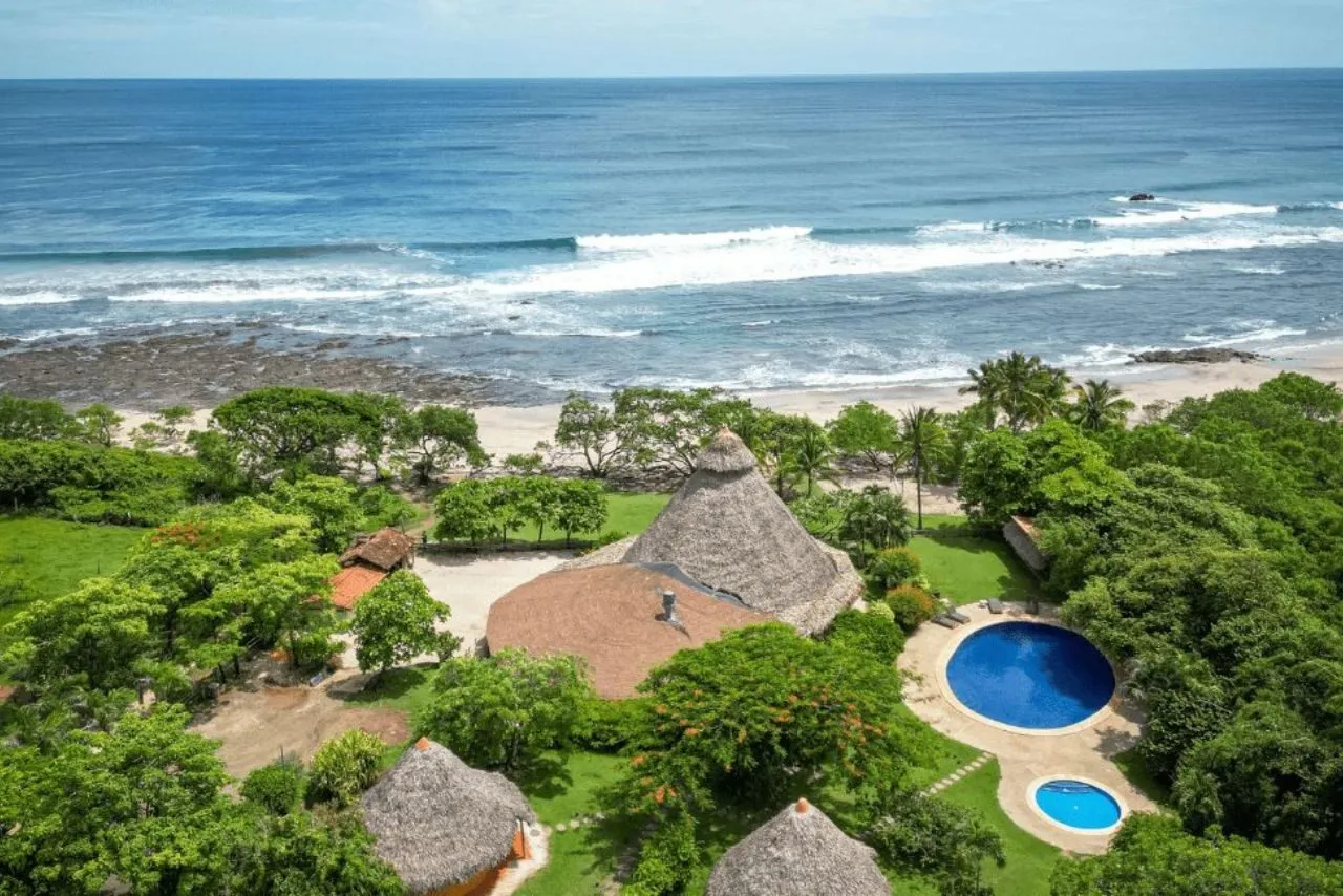 Thatched-roof buildings and a pool set back from the surf at Playa Negra